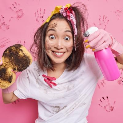 Cheerful Teenage Girl With Pony Tail Smiles Happily Washes Invisible Surface With Spray Detergent Sponge Wears White Spotty T Shirt Has Dirty Face Stands Pink